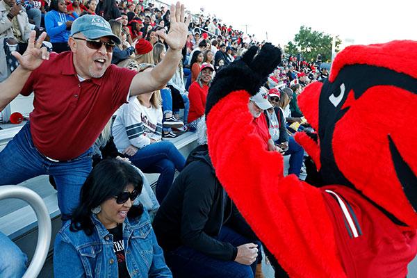 Red mascot giving high five to fan at game