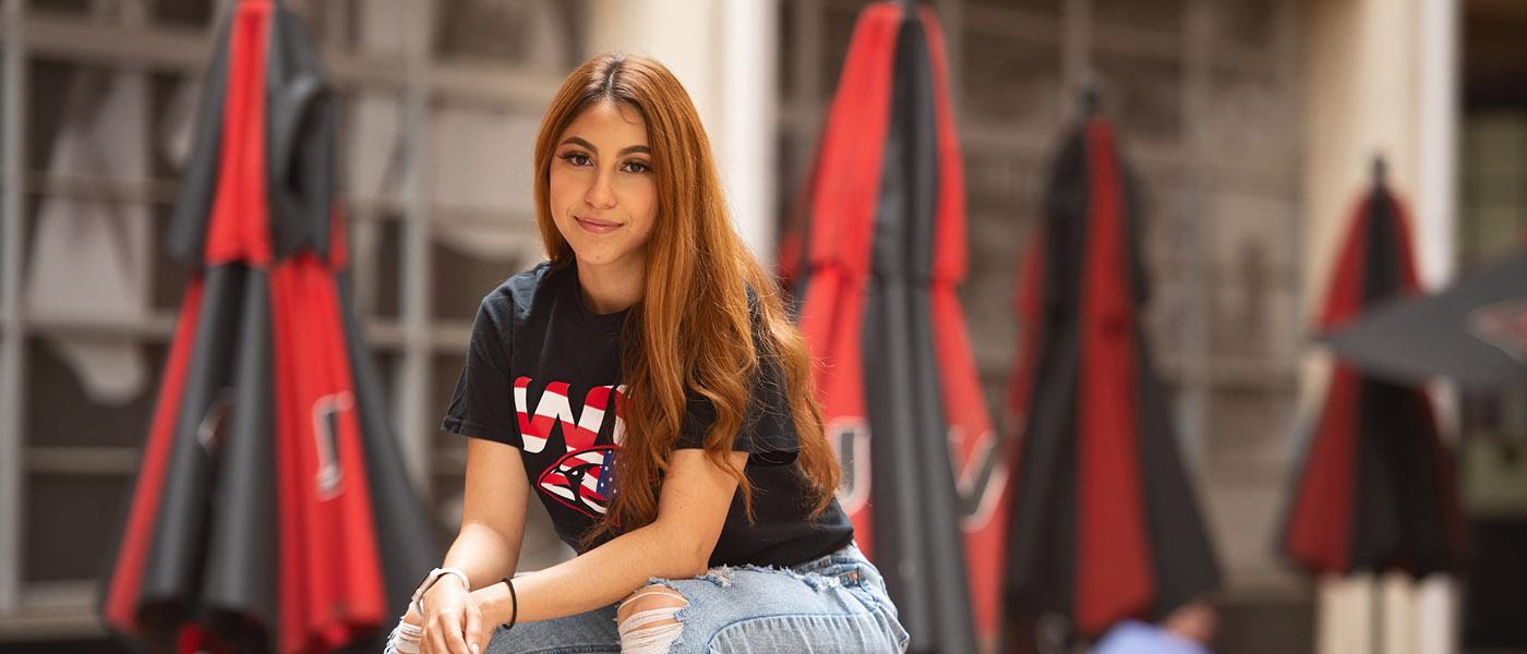 Smiling student sitting on a table at an outdoor courtyard