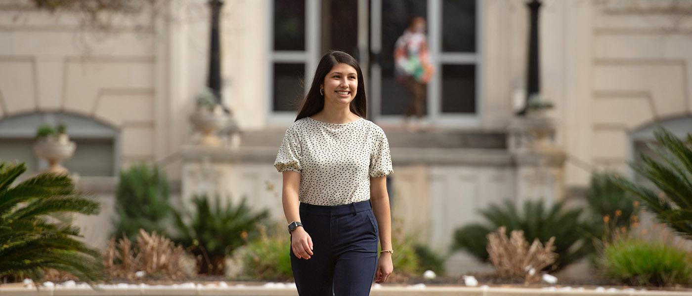 Student walking on campus with the administration building in the background