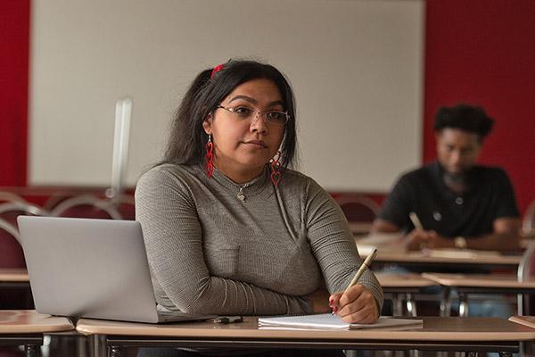 Student at her desk writing on a notebook during class