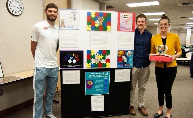 学生 Annie Kramer, Riley Laird and Liam Capobianco pose with their artwork