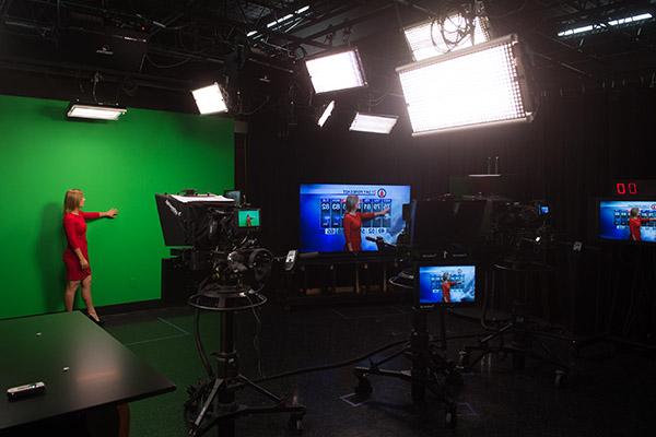 Broadcaster in red dress in studio performing a meteorology broadcast