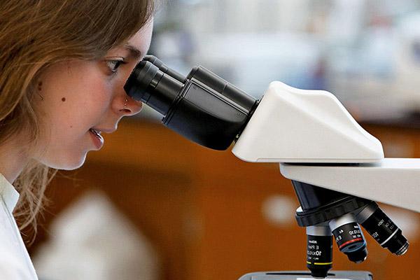 biology student looking through microscope